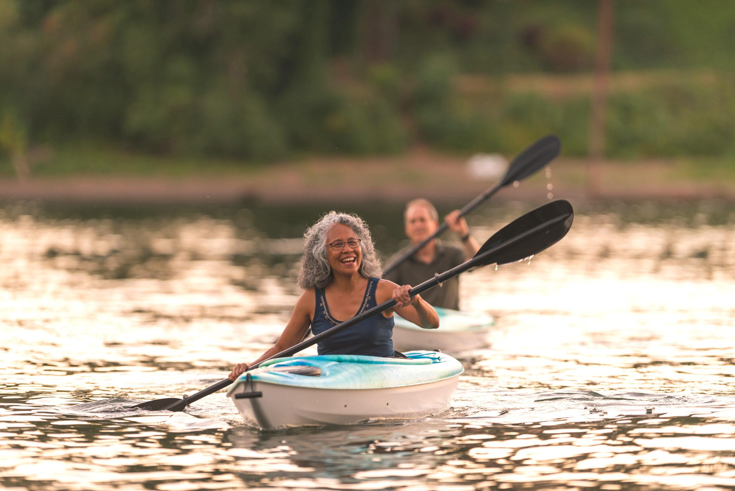 An older couple enjoy a late evening of kayaking on the river.