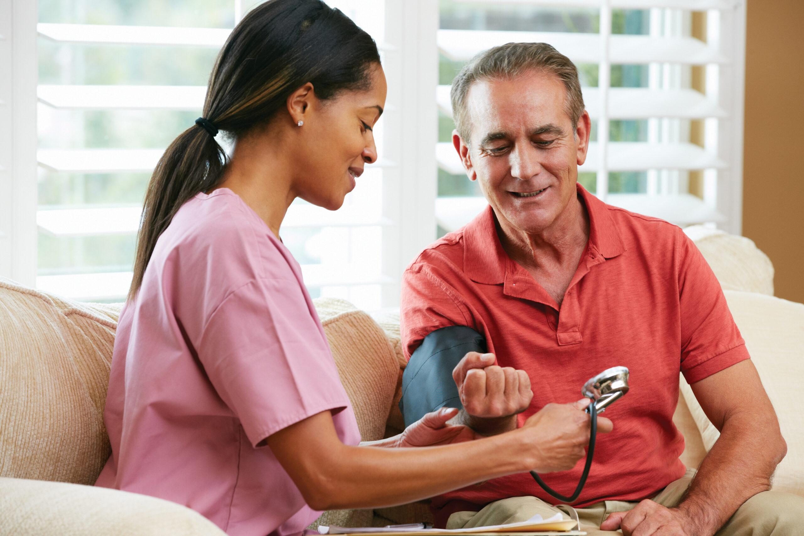 Nurse Visiting Senior Male Patient At Home Taking Blood Pressure