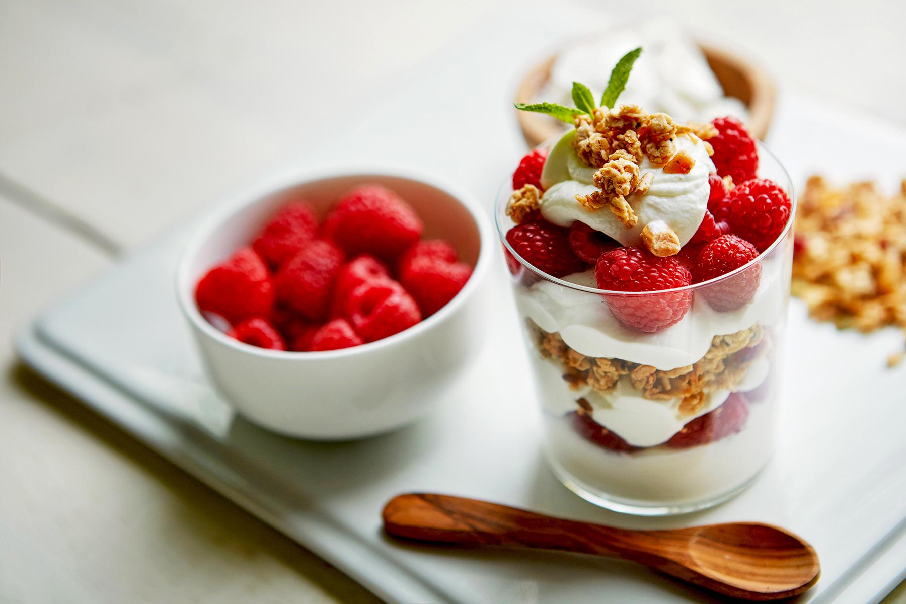 Shot of of granola, yoghurt and berries in a glass and on a plate