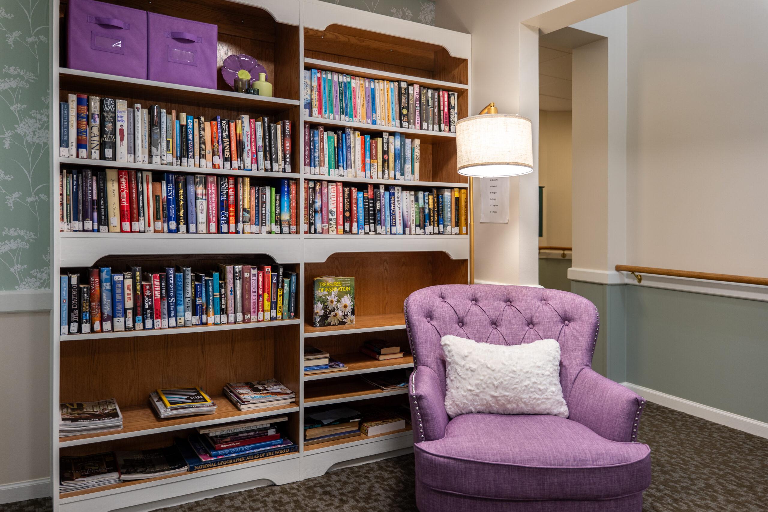 A library and seating area with a purple chair and purple accents.