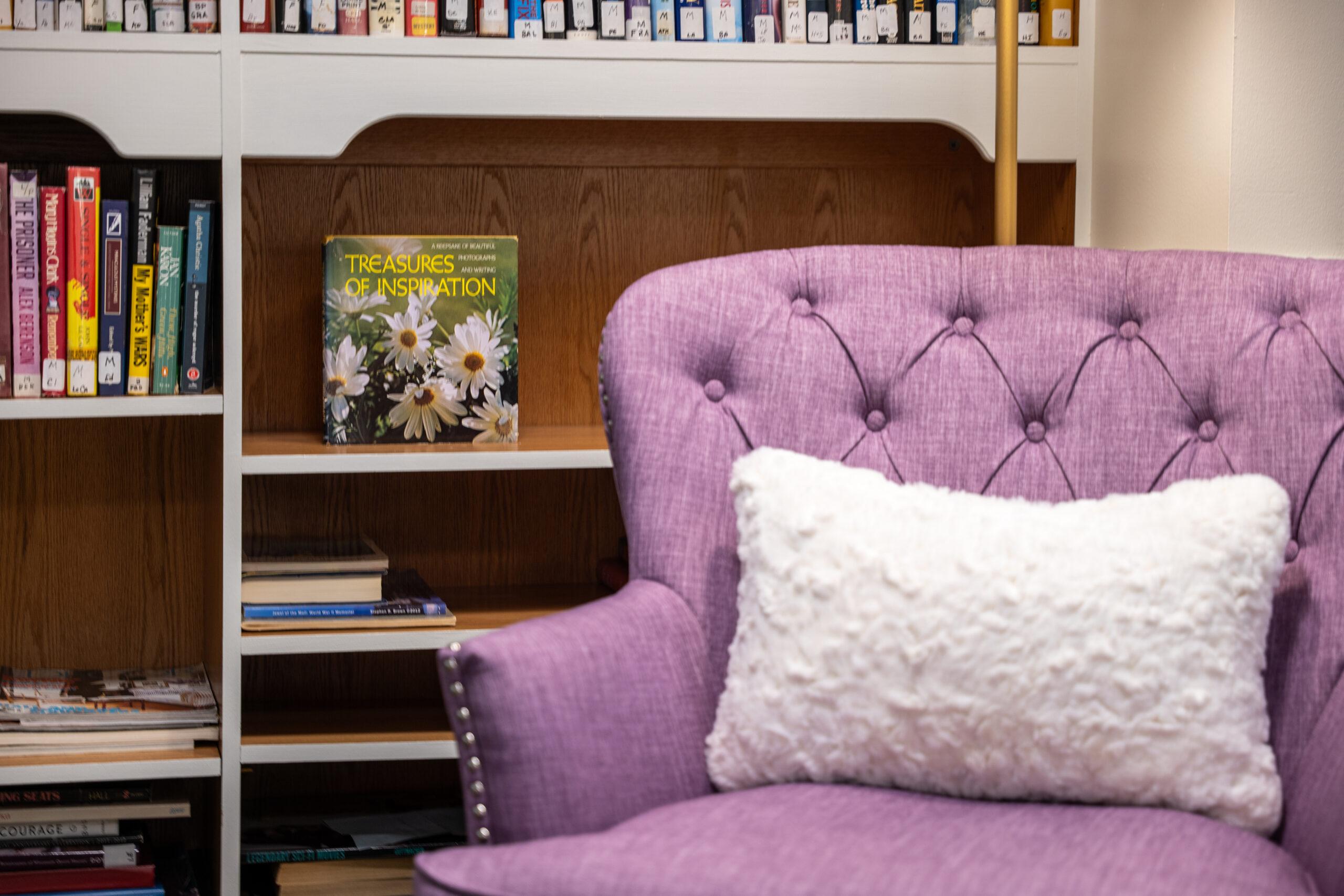 Close-up photo of a purple chair in front of a bookshelf.