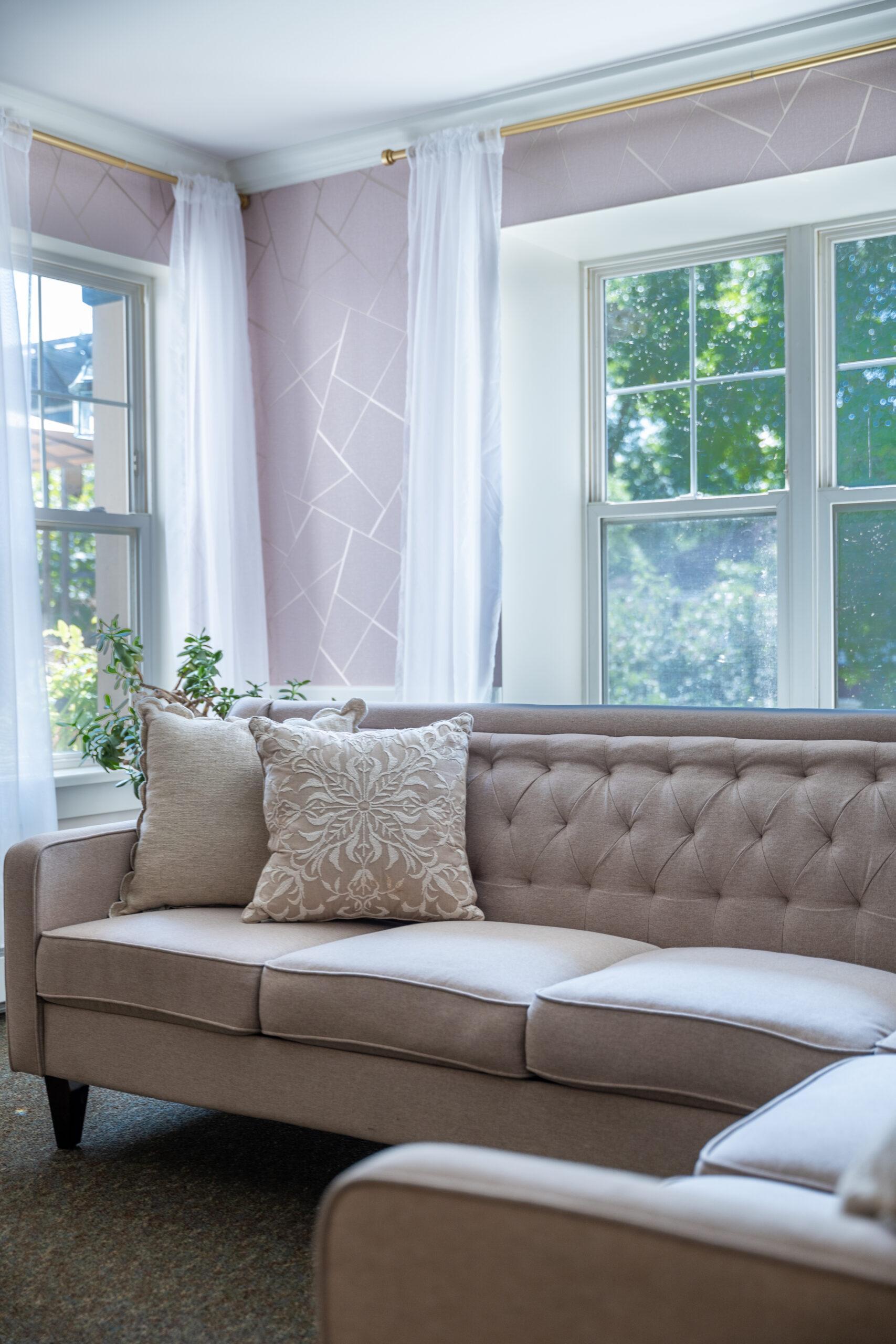 Photo of a couch in a room with pink wallpaper.