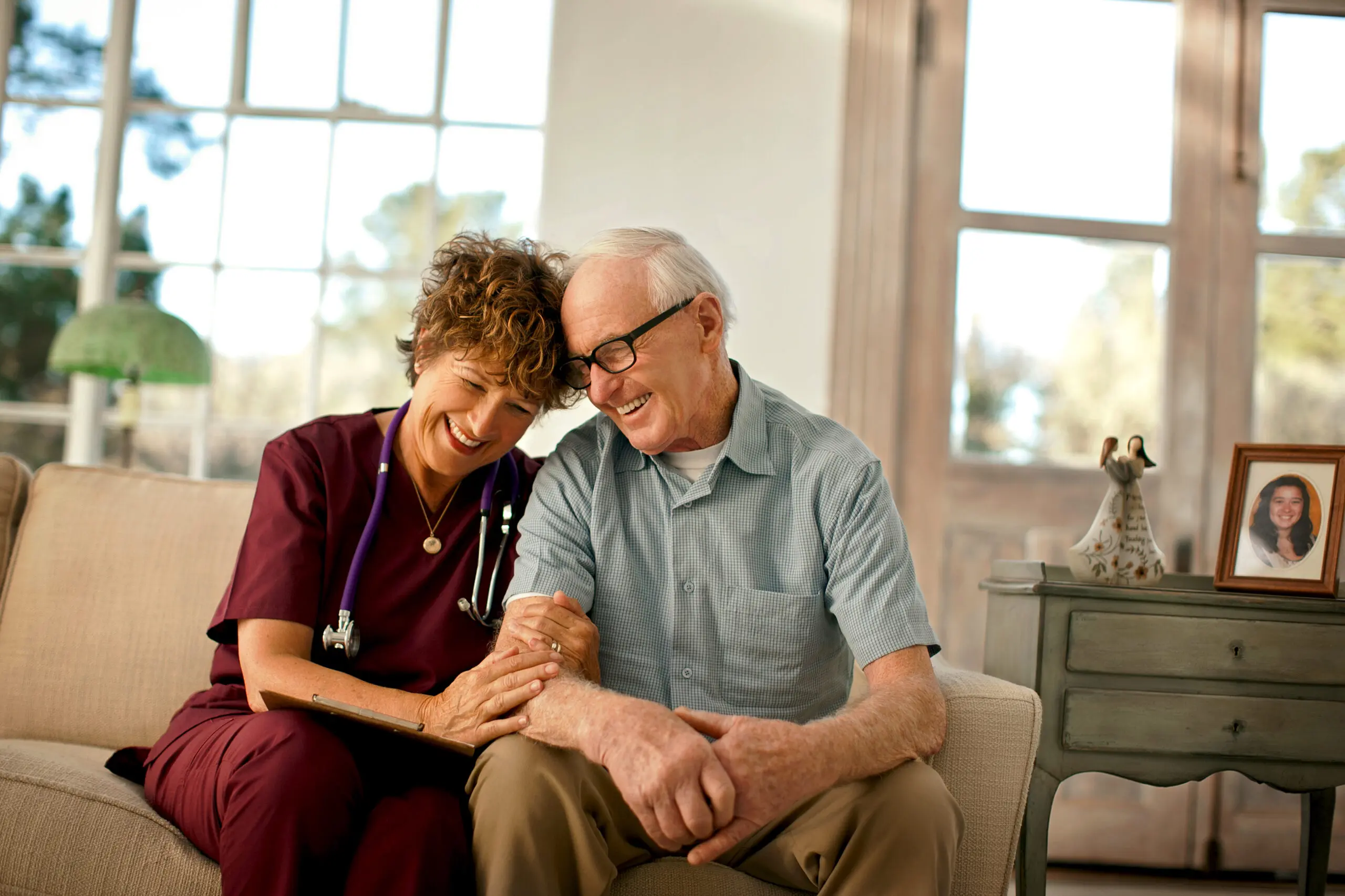 Smiling mature nurse comforting an elderly patient.