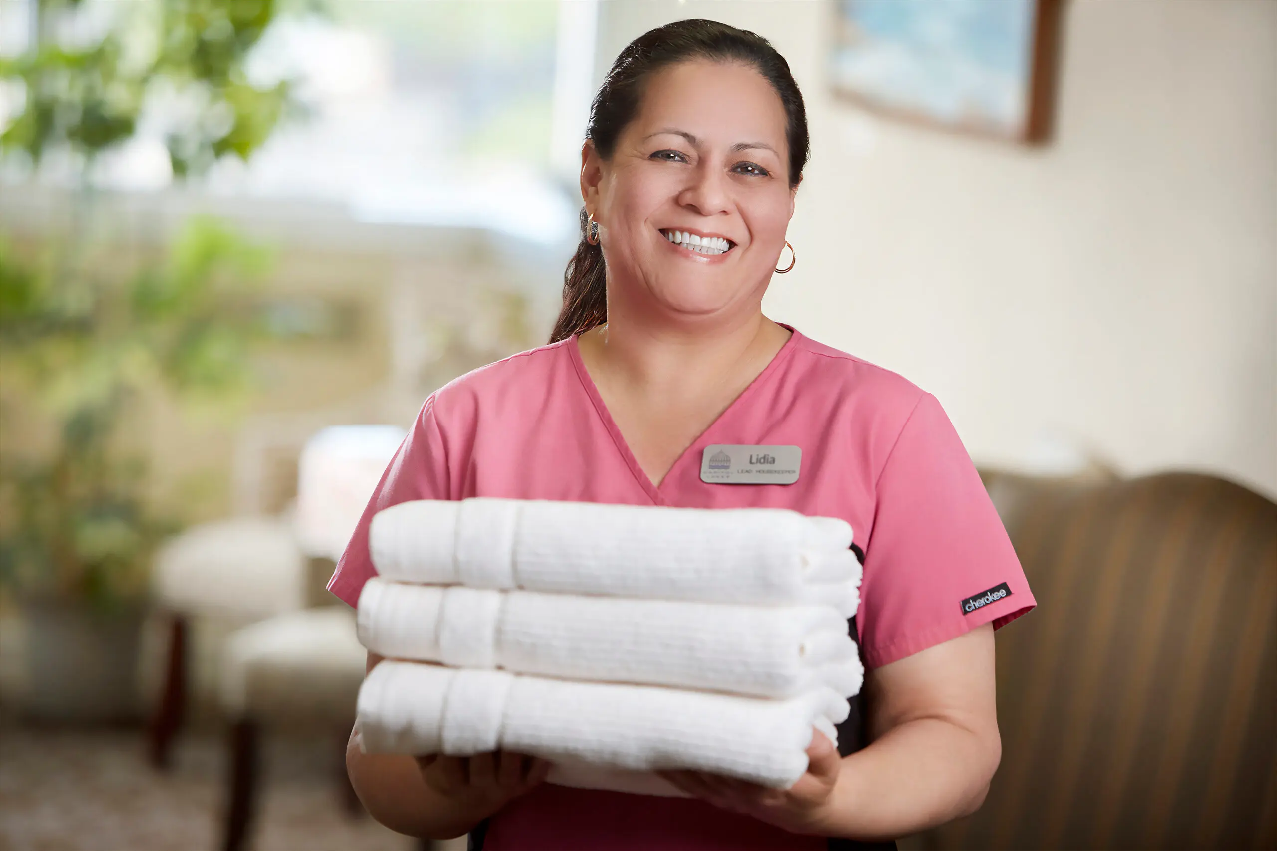 A smiling Capitol Lakes healthcare worker holds a stack of towels.